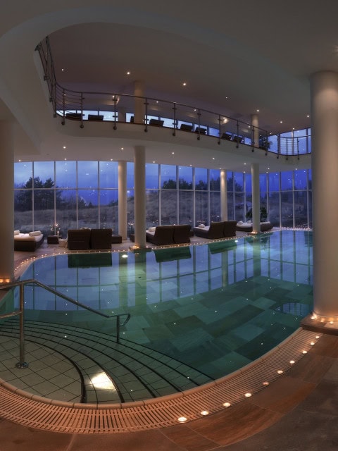 Indoorpool mit Liegeberich im Strandhotel Dünenmeer bei Abenddämmerung