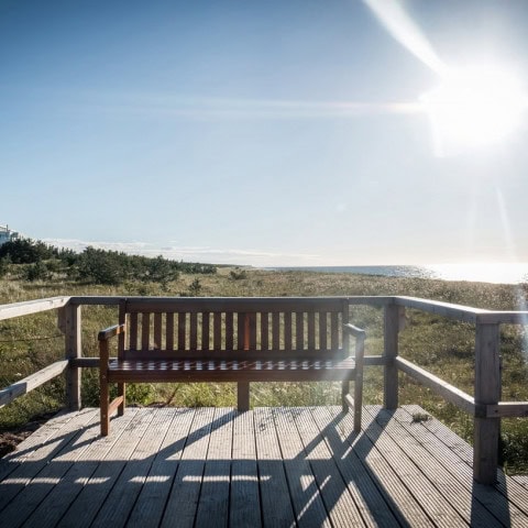 Strandhotel Dünenmeer aus der Ferne mit einer Holzbank im Vordergrund