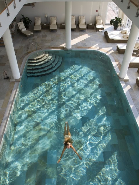 Frau schwimmt im Indoorpool im Strandhotel Dünenmeer